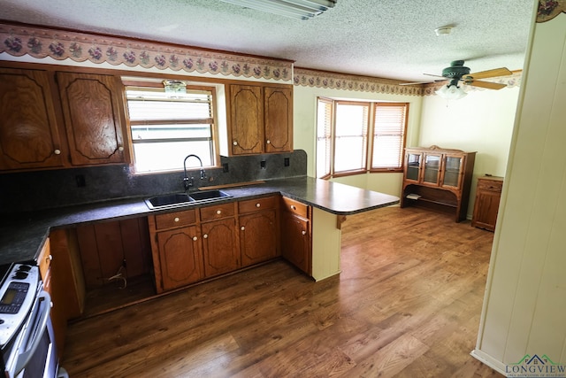 kitchen with dark wood-type flooring, sink, ceiling fan, a textured ceiling, and kitchen peninsula