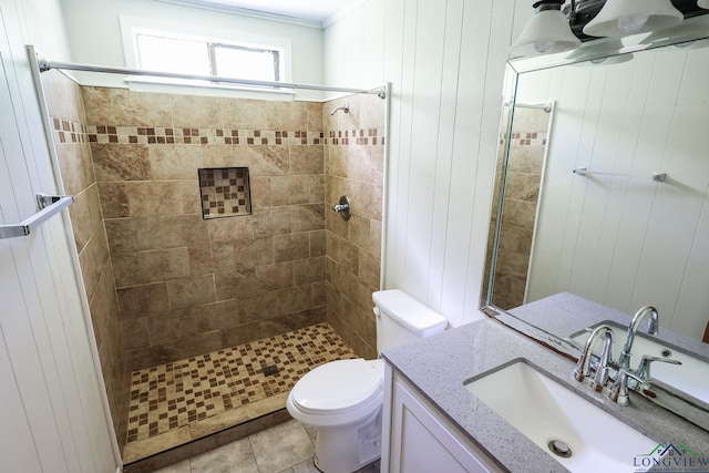 bathroom featuring tiled shower, wood walls, tile patterned flooring, and toilet