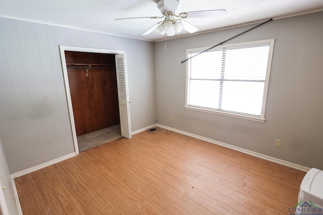 unfurnished bedroom featuring hardwood / wood-style flooring, ceiling fan, ornamental molding, and a closet