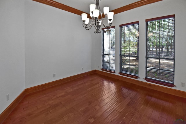 empty room with hardwood / wood-style floors, a wealth of natural light, and an inviting chandelier