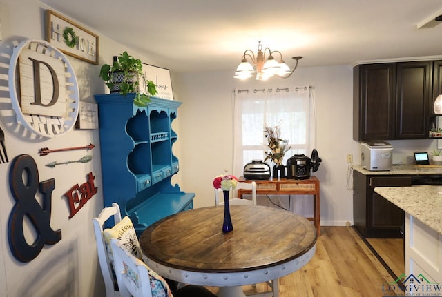 dining space with light wood-type flooring and an inviting chandelier