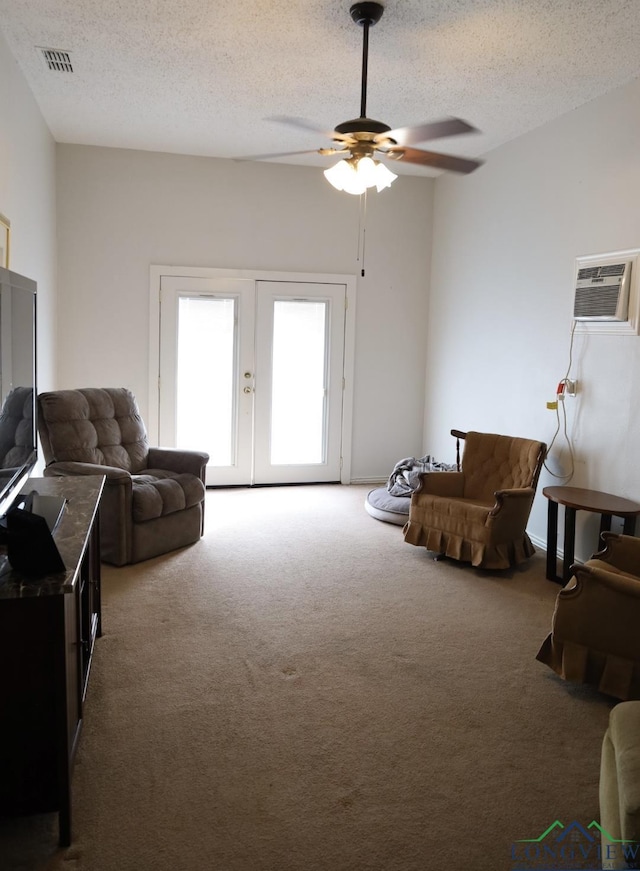 carpeted living room with french doors, a textured ceiling, an AC wall unit, and ceiling fan