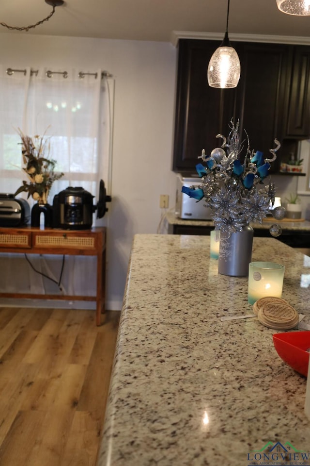 kitchen featuring light stone countertops, decorative light fixtures, and light wood-type flooring