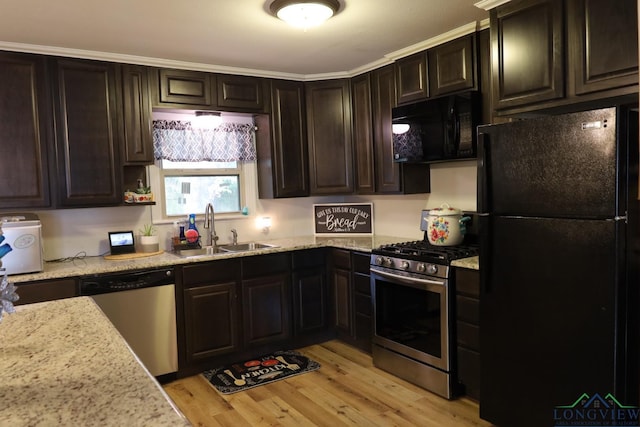 kitchen featuring light wood-type flooring, ornamental molding, dark brown cabinets, sink, and black appliances