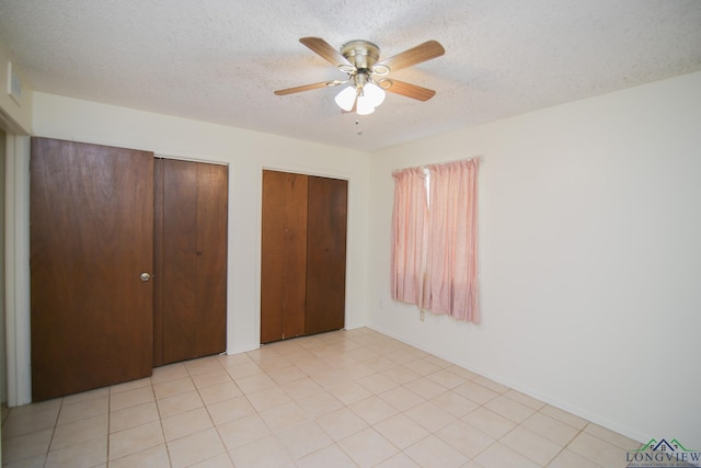 unfurnished bedroom featuring multiple closets, ceiling fan, and a textured ceiling