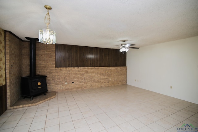 unfurnished living room with wood walls, ceiling fan, light tile patterned floors, a textured ceiling, and brick wall