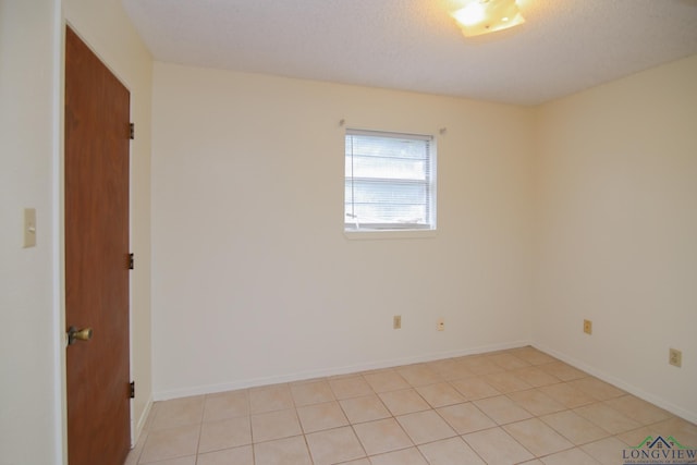 spare room featuring light tile patterned floors and a textured ceiling