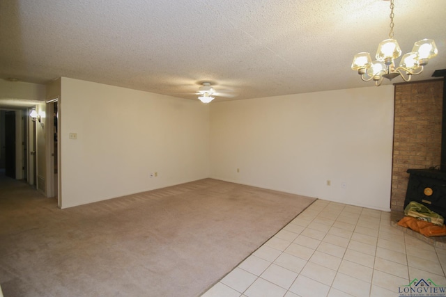 unfurnished living room featuring a textured ceiling, ceiling fan with notable chandelier, light colored carpet, and a wood stove