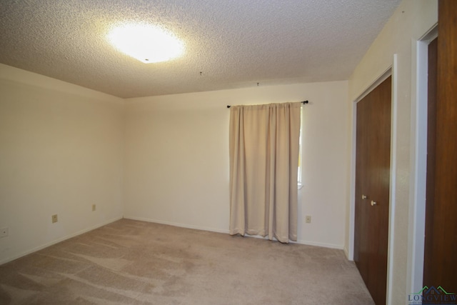 carpeted empty room featuring a textured ceiling