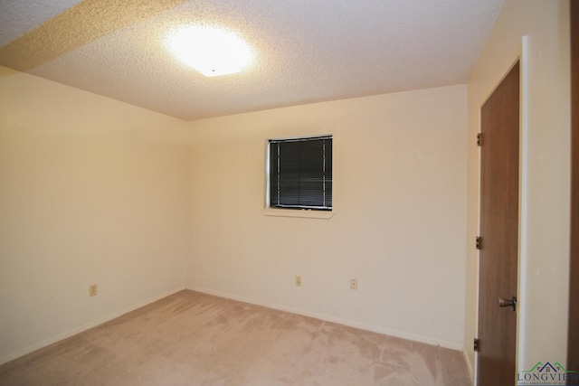 empty room with light colored carpet and a textured ceiling