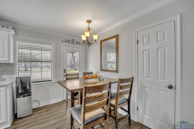 dining area featuring crown molding, a notable chandelier, and light hardwood / wood-style floors