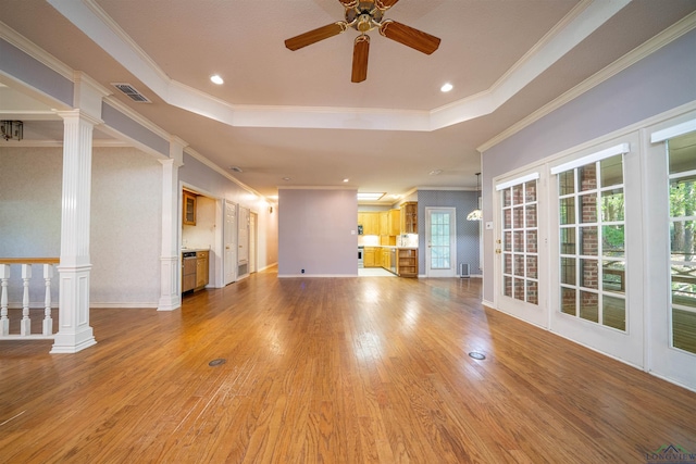 9211 Elm Tree Cir, Tyler, TX 75703 - unfurnished living room featuring a ceiling fan, a tray ceiling, ornamental molding, light wood-style floors, and decorative columns