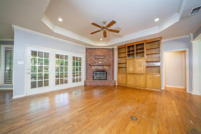 9211 Elm Tree Cir, Tyler, TX 75703 - unfurnished living room with a raised ceiling, ceiling fan, ornamental molding, light wood-style flooring, and a fireplace