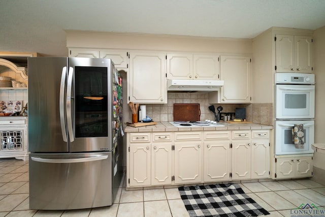 3365 Omie Dr, Longview, TX 75605 - kitchen featuring white appliances, under cabinet range hood, tile countertops, light tile patterned flooring, and ornamental molding