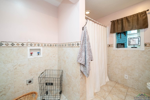 3365 Omie Dr, Longview, TX 75605 - bathroom with tile walls, toilet, curtained shower, tile patterned floors, and a wainscoted wall