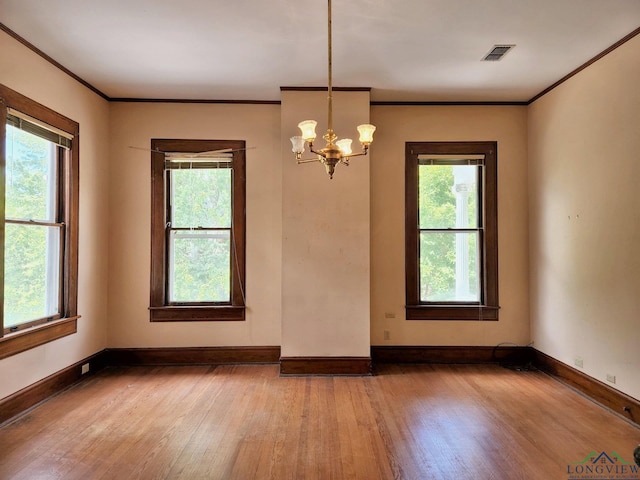 spare room featuring crown molding, hardwood / wood-style floors, and a notable chandelier