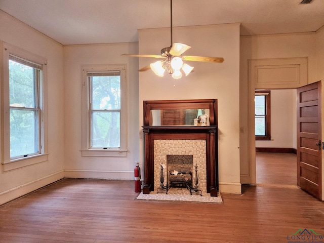 unfurnished living room featuring a tile fireplace, hardwood / wood-style flooring, and ceiling fan