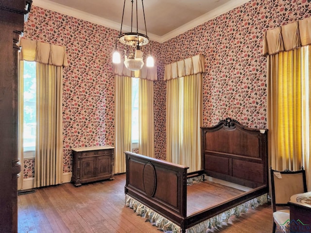 bedroom with hardwood / wood-style floors, ornamental molding, and a chandelier