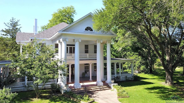 view of front of property featuring covered porch, a balcony, and a front yard