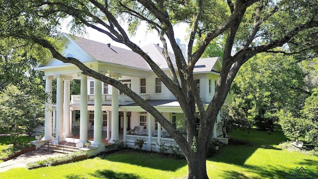 view of front of home with covered porch, a balcony, and a front yard