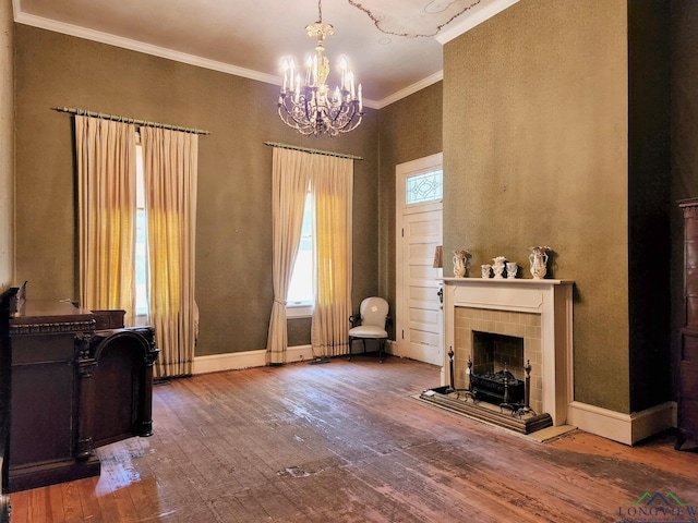 living area with a chandelier, a fireplace, wood-type flooring, and ornamental molding