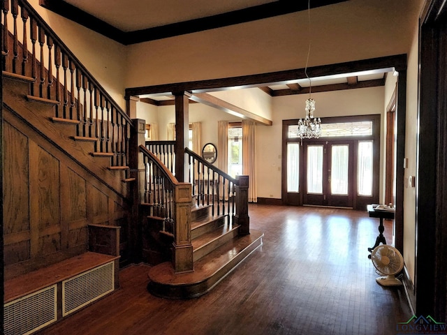 foyer featuring beamed ceiling, dark hardwood / wood-style flooring, and an inviting chandelier