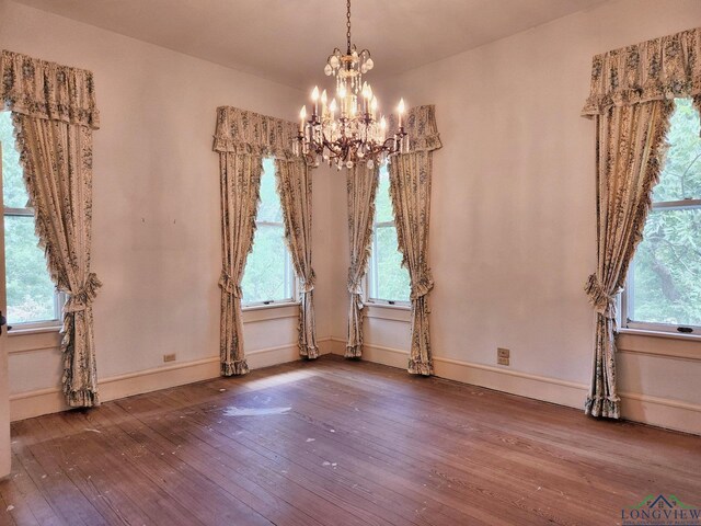 spare room featuring hardwood / wood-style flooring, an inviting chandelier, and plenty of natural light