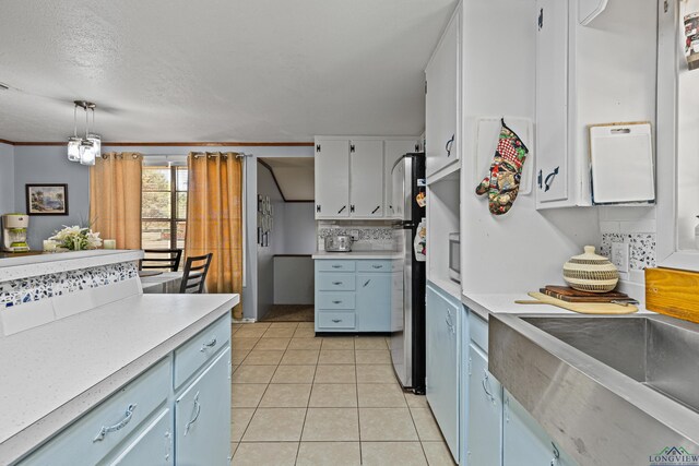 kitchen with pendant lighting, stainless steel refrigerator, white cabinetry, light tile patterned flooring, and decorative backsplash