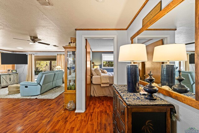 interior space featuring ceiling fan, ornamental molding, dark hardwood / wood-style floors, and a textured ceiling