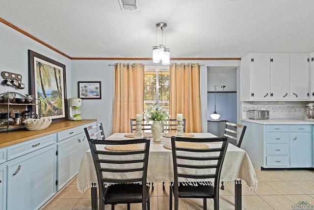 dining area featuring ornamental molding, a textured ceiling, and light tile patterned floors