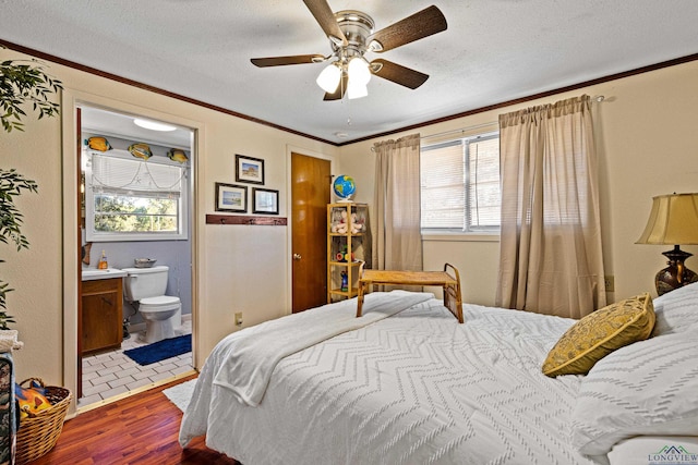 bedroom with hardwood / wood-style floors, ensuite bath, ornamental molding, and a textured ceiling