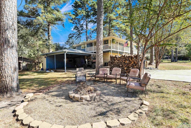 back of property featuring a yard, a fire pit, a carport, and a balcony