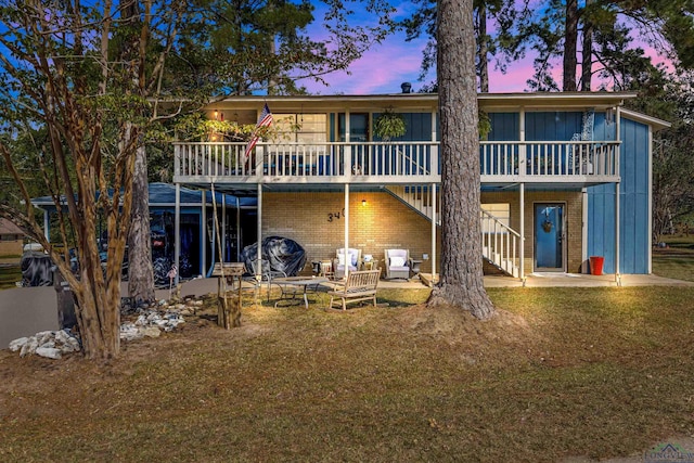 back house at dusk featuring a yard and a patio area