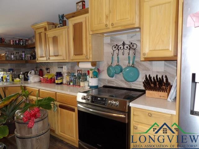 kitchen with tasteful backsplash, refrigerator, and stainless steel range with electric cooktop