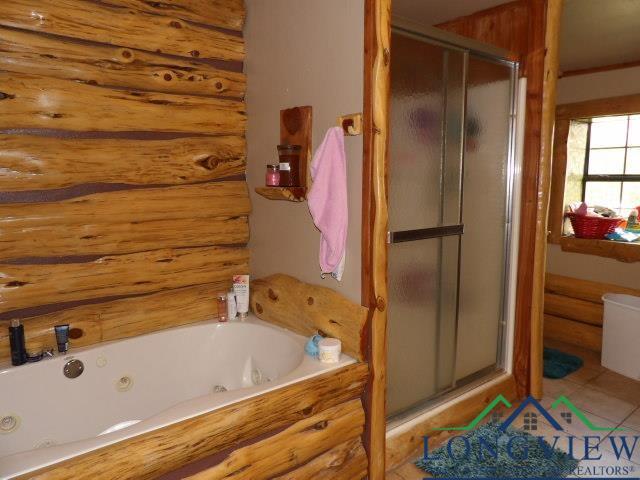 bathroom with a shower with door and log walls