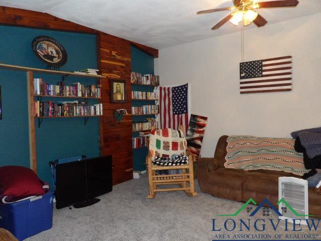 carpeted living room featuring ceiling fan and lofted ceiling