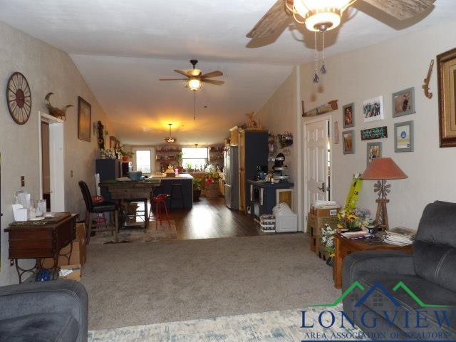 living room featuring ceiling fan, carpet floors, and vaulted ceiling