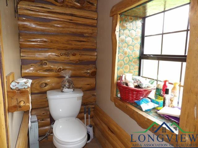 bathroom featuring log walls, toilet, and a healthy amount of sunlight