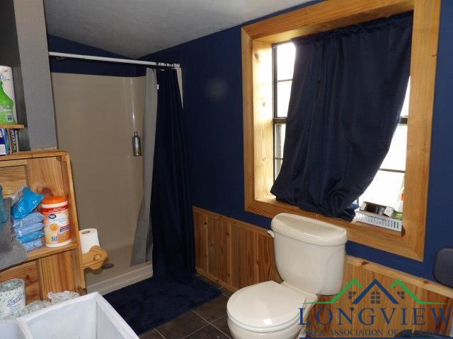 bathroom featuring tile patterned flooring, vaulted ceiling, toilet, and walk in shower