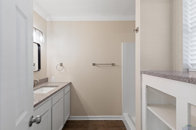 bathroom with baseboards, ornamental molding, wood finished floors, and vanity