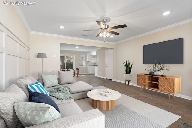 living area featuring visible vents, a ceiling fan, baseboards, ornamental molding, and dark wood-style floors