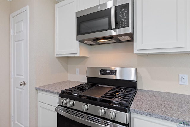 kitchen with light stone countertops, appliances with stainless steel finishes, and white cabinets