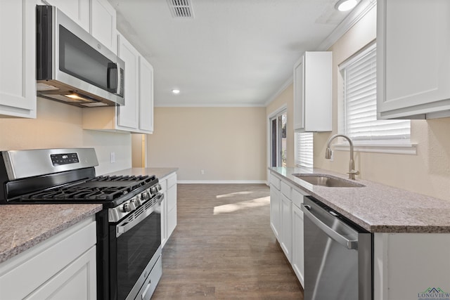 kitchen with light countertops, appliances with stainless steel finishes, a sink, and white cabinets