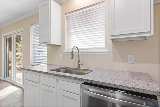 kitchen with light stone counters, ornamental molding, a sink, white cabinetry, and stainless steel dishwasher