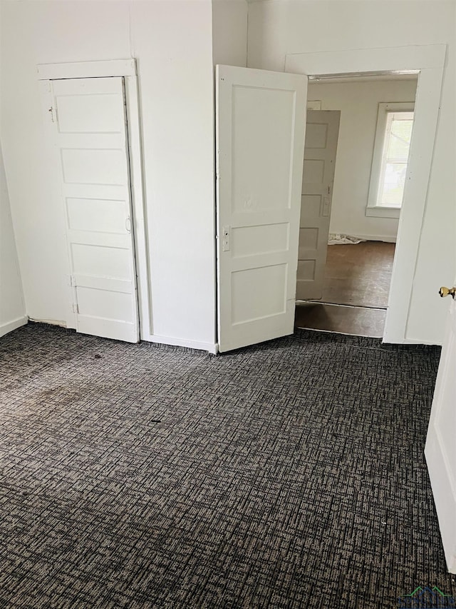 unfurnished bedroom featuring dark colored carpet and a closet