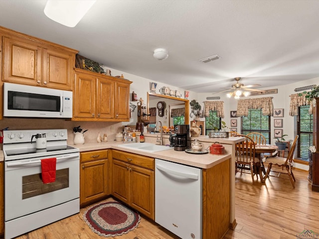 kitchen featuring kitchen peninsula, sink, white appliances, and light hardwood / wood-style flooring