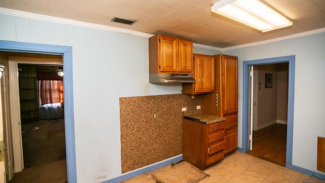 kitchen featuring ornamental molding, light tile patterned floors, and dark stone counters