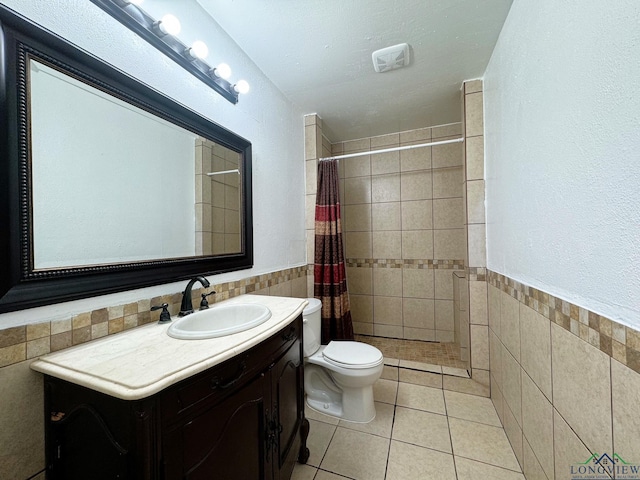 bathroom with tile walls, tile patterned flooring, vanity, walk in shower, and toilet