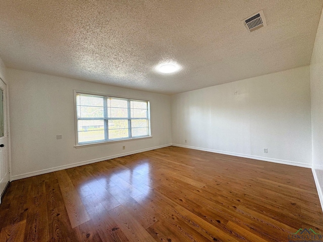 empty room featuring dark wood-type flooring and a textured ceiling