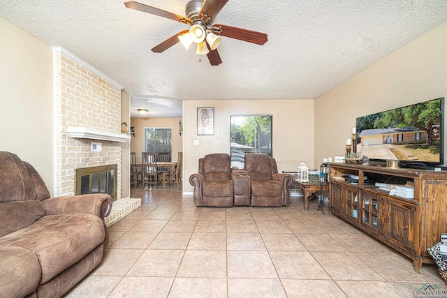 living room featuring ceiling fan, light tile patterned floors, a textured ceiling, and a brick fireplace